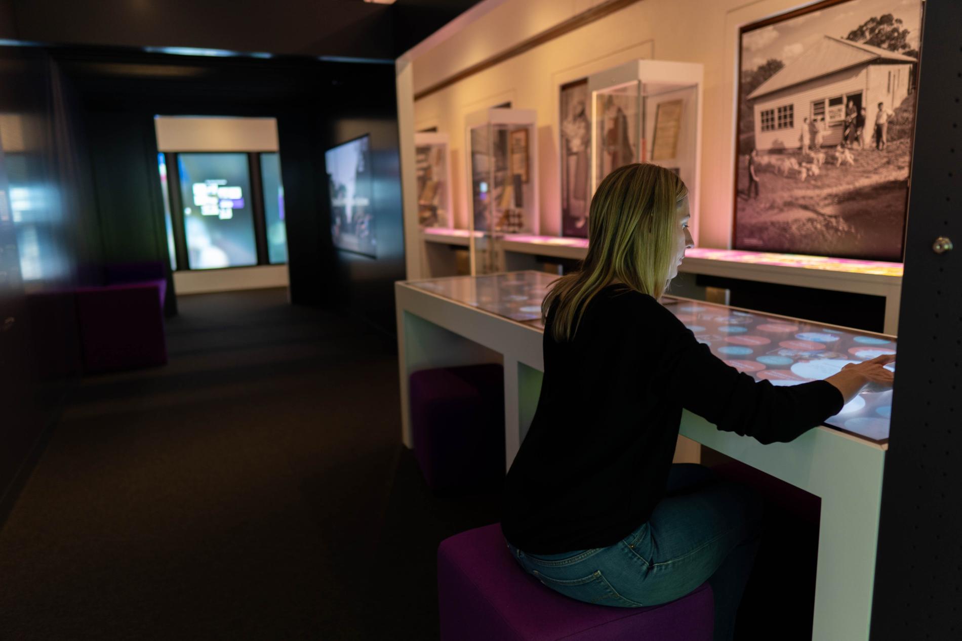 A woman is sitting and interacting with a touchscreen in an exhibition A woman is sitting and interacting with a touchscreen in an exhibition