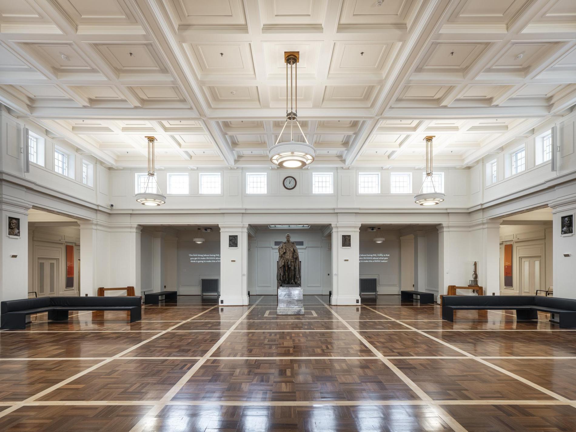 Kings Hall: a parquetry floor greets visitors, as they walk in to the spacious hall with the statue of King George V the main focal point. On either side of the statue sit two right-angled black leather seats for visitors to sit and take in the architectural details, including the pendant lights, clerestory windows and detailed geometric ceiling.