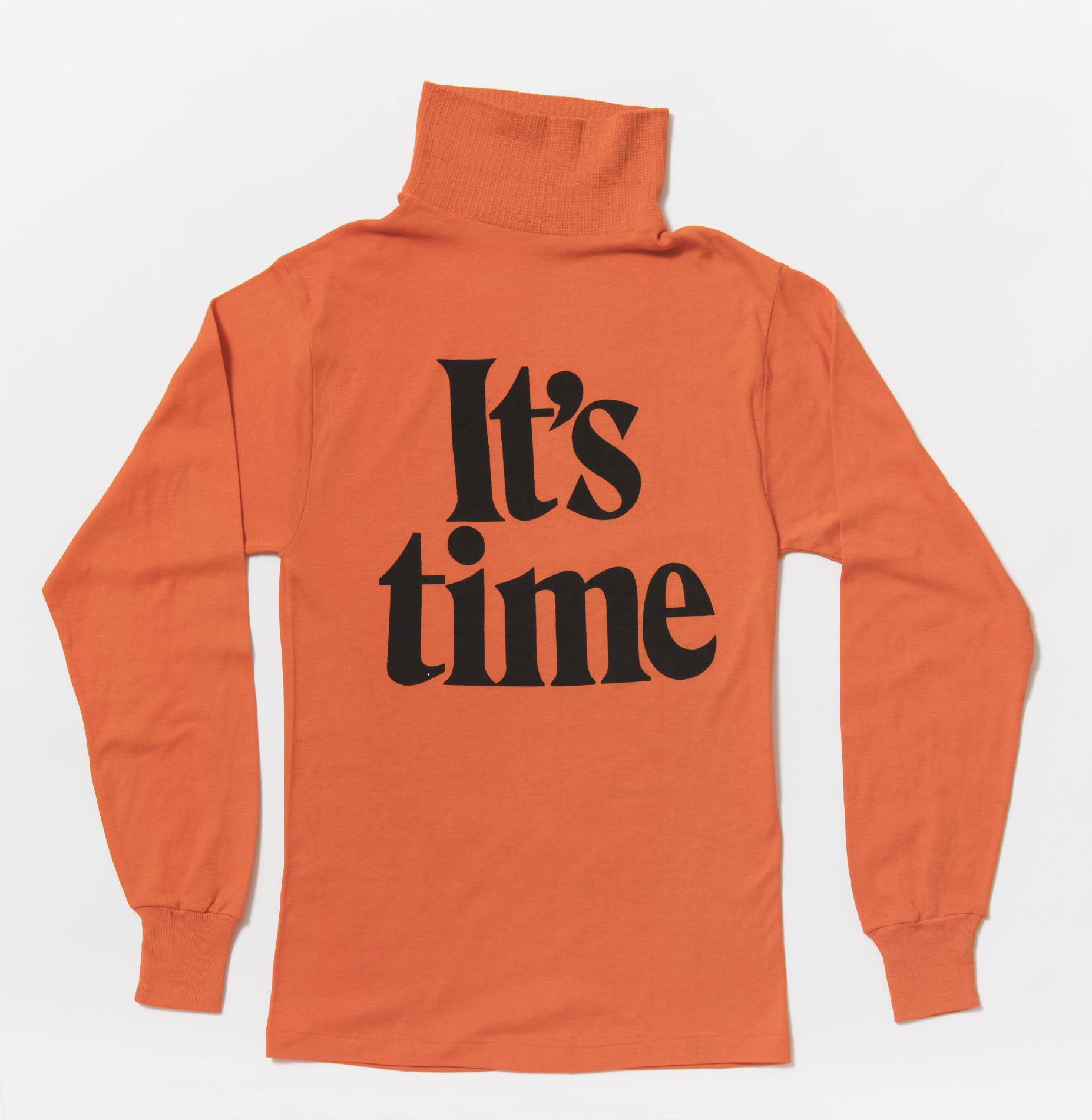 A bright orange long-sleeved skivvy with the words 'It's time' in big black font on the front.