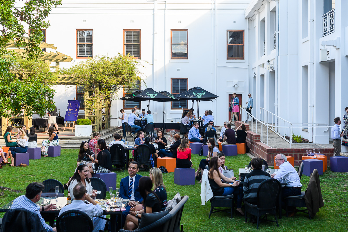 People sit at tables and on stools in the Old Parliament House courtyard having drinks. People sit at tables and on stools in the Old Parliament House courtyard having drinks.