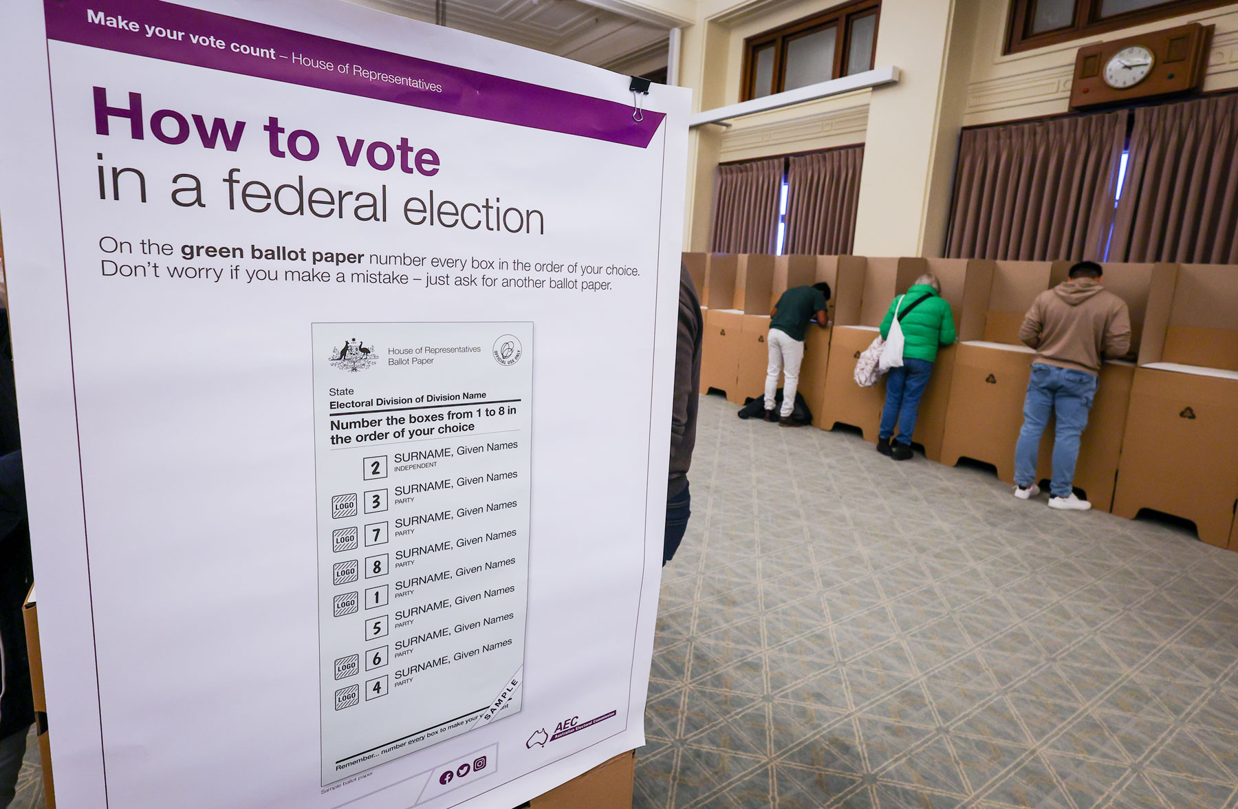 A large white poster with voting instructions for a federal election is displayed near cardboard polling booths in Old Parliament House.